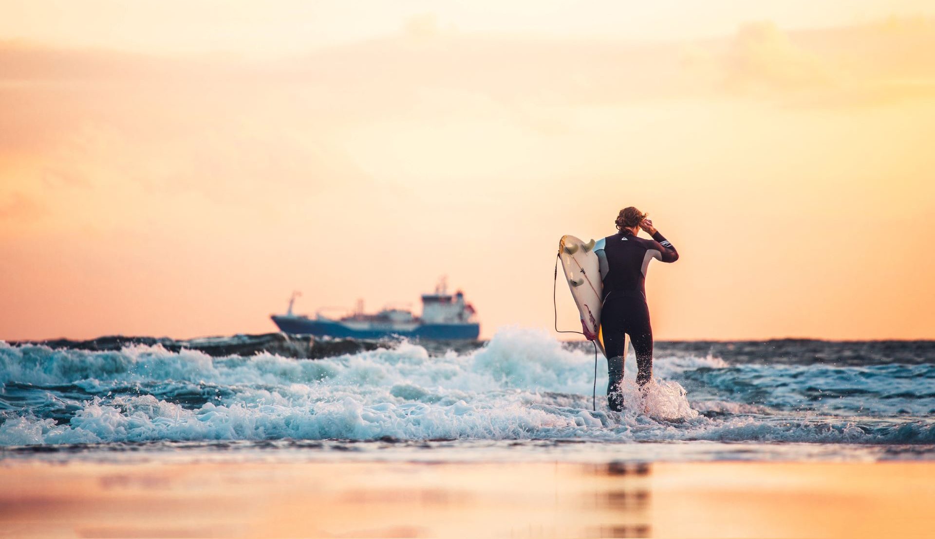 Surfer am Strand mit Schiff im Hintergrund